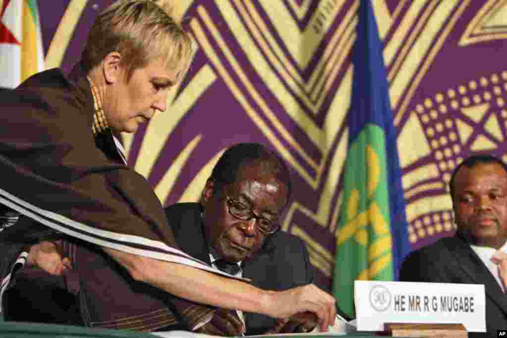 President of Zimbabwe, Robert Mugabe, centre at the signing of the power sharing deal between him and Morgan Tsvangirai in Harare Monday, Sept, 15, 2008. Looking on , on the right is King Mswati 111 of Swaziland.