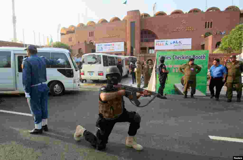 ورلڈ الیون کے کھلاڑیوں کی قذافی اسٹیڈیم آمد سے قبل ایک سکیورٹی اہلکار تربیتی مشق میں پوزیشن لیے ہوئے ہے