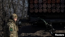 Ukrainian serviceman stands next to a BM-21 Grad multiple launch rocket system before firing towards Russian troops in Donetsk region