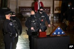 U.S. Capitol Police officers pay their respects to U.S. Capitol Police officer Brian Sicknick as an urn with his cremated remains lies in honor on a black-draped table at the center of the Capitol Rotunda, Wednesday, Feb. 3, 2021, in Washington. …