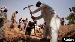 FILE - Members of the Ahmadiyya Muslim community dig graves for victims in Chenab Nagar, in Punjab's Chiniot district, about 200 km (124 miles) northwest of Lahore, May 29, 2010. Gunmen attacked Ahmadiyya worshippers in two Lahore mosques the day before, taking hostages and killing at least 70 people, officials said. 