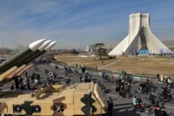 Iranians drive past missiles by their motorcycle during a rally marking the 42nd anniversary of the Islamic Revolution, at Azadi (Freedom) Square in Tehran, Iran, Feb. 10, 2021.
