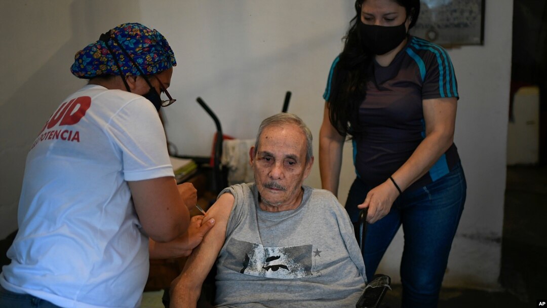 Un trabajador de la salud inocula a un anciano con una dosis de la vacuna Sputnik V COVID-19, en su casa del barrio 23 de Enero en Caracas. Junio 12, 2021.