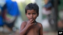 FILE - A child eats a pomegranate collected from waste at a slum area on the outskirts of Jammu, India, Oct. 12, 2018. 