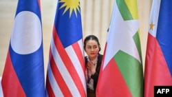 A police official looks on between national flags during the Association of Southeast Asian Nations summit in Vientiane, Laos, on Oct. 9, 2024. One topic of discussion for the ASEAN representatives will be proposed additions to the group's free-trade agreement with China.