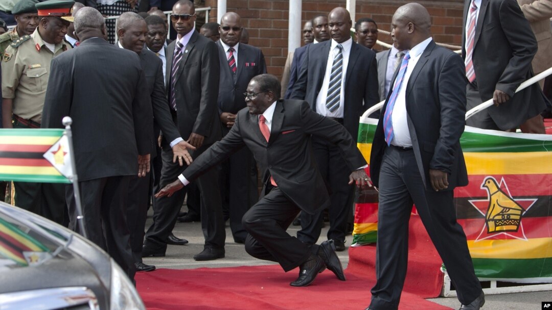 Zimbabwean President Robert Mugabe, center, falls after addressing supporters, at Harare International Airport upon his return from an African Union summit in Ethiopia, Feb. 4, 2015.