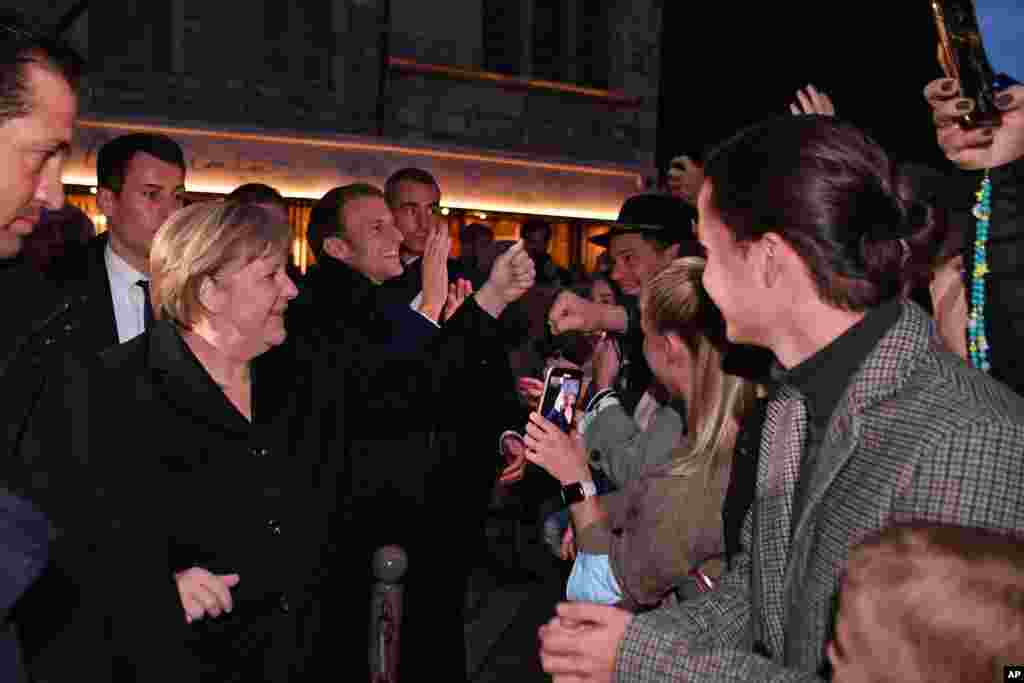 French President Emmanuel Macron, center, and German Chancellor Angela Merkel meet residents in Beaune, Burgundy. Merkel will be feted by France in a special farewell ceremony honoring her leadership and partnership. Merkel is leaving office after 16 years in power.&nbsp;