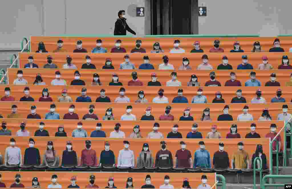 A man walks past banners depicting spectators in the stands prior to the opening game between the SK Wyverns and the Hanwha Eagles at the opening game of South Korea&#39;s new baseball season, in Incheon.