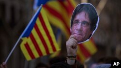 Seorang demonstran membawa topeng mantan Presiden Catalonia Carles Puigdemont saat melakukan unjuk rasa di luar gedung parlemen Catalonia di Barcelona (foto: ilustrasi). 