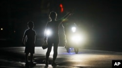 (FILE) A woman and a boy attempt to hitch a ride during a scheduled power outage in Bauta, Cuba. 