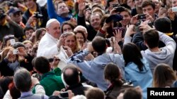 Pope Francis waves as he arrives to lead a weekly general audience in Saint Peter's Basilica at the Vatican, April 3, 2013.