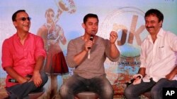 FILE - Director Rajkumar Hirani, (R), and producer Vidhu Vinod Chopra, (L), enjoy a lighter moment as Bollywood actor Aamir Khan speaks during the unveiling of the second poster of his upcoming film "PK" in Mumbai, India, Aug. 20, 2014.