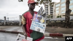 Un marchand de journaux à Libreville le 29 août 2016 tout en affichant des journaux locaux rapportant le résultat des élections présidentielles au Gabon.