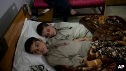 Abdul Rasheed, 9, front, and Shoaib Ahmed, 13, lie in a bed at a hospital in Islamabad, Pakistan, May 5, 2016. The boys, active during the day, lapse into a vegetative state after sunset. Dr. Javed Akram told AP he has no idea what is causing the symptoms.