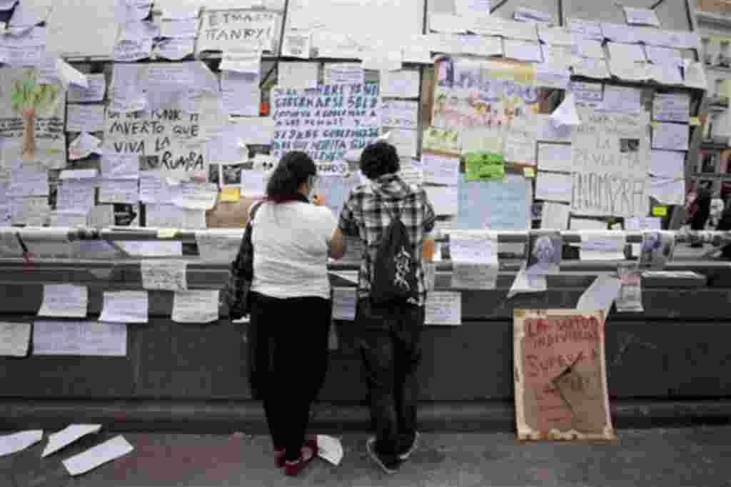 La gente lee los carteles en la plaza de Sol en Madrid, 19 de mayo 2011.