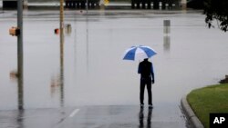 A man surveys floodwaters caused by heavy rains, May 25, 2013, in San Antonio.