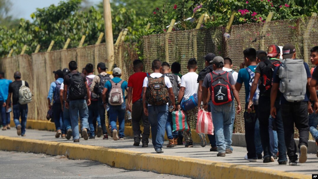 FILE - Central American migrants cross into Mexico from Guatemala, near Ciudad Hidalgo, Mexico, June 4, 2019. The migrants walked over the bridge and waited to register at a Mexican immigration office.