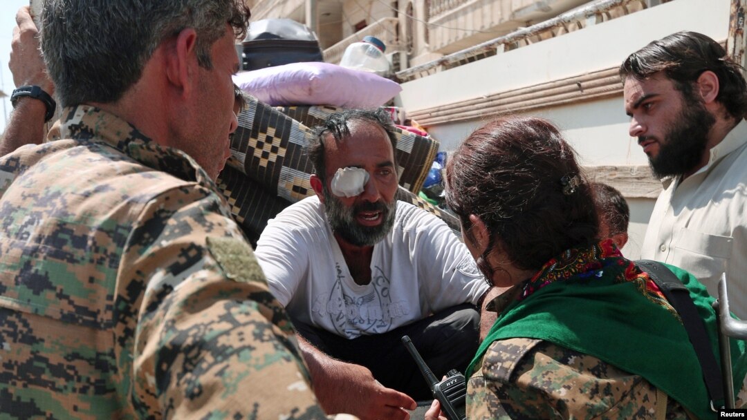 Pejuang Pasukan Demokrasi Suriah (SDF) berbicara dengan warga sipil yang terluka di Manbij, Suriah utara (12/8). 