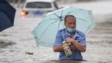 TOPSHOT - This photo taken on July 20, 2021 shows a man wading through flood waters along a street following heavy rains in Zhengzhou in China's central Henan province. (Photo by STR / AFP) / China OUT