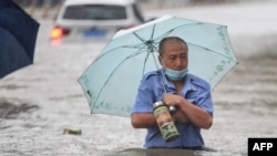 A man wades through flood waters along a street following heavy rains in Zhengzhou in China's central Henan province, July 20, 2021.