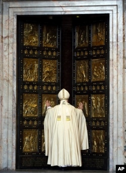 FILE - Pope Francis pushes open the Holy Door of St. Peter's Basilica, formally launching the Holy Year of Mercy, at the Vatican, Dec. 8, 2015.