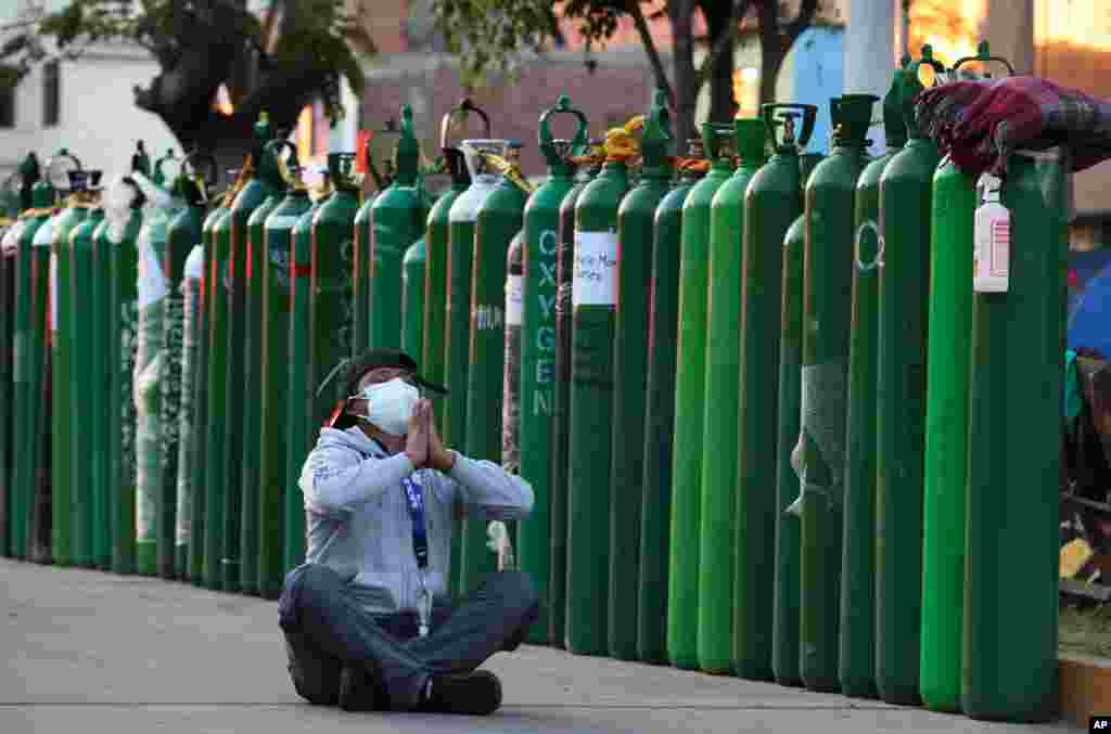 페루 카야오의 산소 충전소에서 신종 코로나바이러스에 감염된 가족을 위한 산소를 구하기 위해 사흘 째 줄에서 차례를 기다리던 남성이 기도하고 있다.