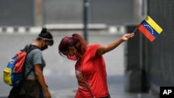 Una mujer con un tapabocas sostiene una bandera venezolana durante el Día de la Independencia en Caracas, el 5 de julio de 2020..