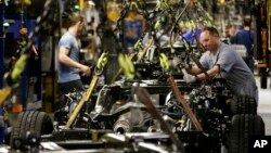 File - A worker prepares a chassis to receive an engine at Ford's Kansas City Assembly Plant in Claycomo, Missouri, March 2015.