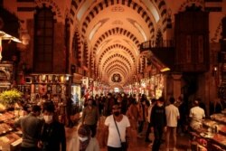 People wearing masks for protection against the spread of coronavirus, walk in the Spice Market, or the Egyptian Bazaar, in Istanbul, Nov. 17, 2020.