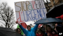 A protester holds a banner reading " Stop of state of emergency" during a protest in Paris, Jan. 30, 2016.