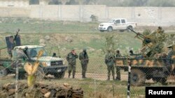 FILE - Fighters loyal to Syria's President Bashar al-Assad stand near military vehicles after regaining control of Deir al-Adas, a town south of Damascus, Dara'a countryside Feb. 10, 2015.