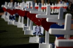 FILE - A photograph hangs from one of the 58 white crosses set up for the victims of the Route 91 music festival mass shooting in Las Vegas, Oct. 5, 2017.