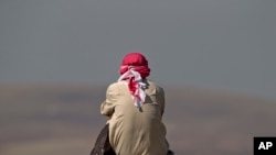 Seorang pria menonton pertempuran di Kobani dari bukit di pinggiran Suruc, dekat perbatasan Turki-Suriah, 24 Oktober 2014. 