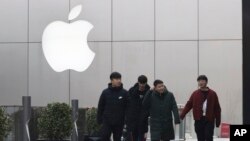 FILE - Men walk past an Apple logo in Beijing, China, Jan. 3, 2019.