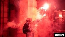 Demonstrator throws a flare towards riot police during a protest in front of the City Hall building in Novi Sad, Serbia, Nov. 5, 2024.