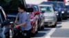 A customer pumps gas at Costco, as others wait in line, in Charlotte, N.C., May 11, 2021.