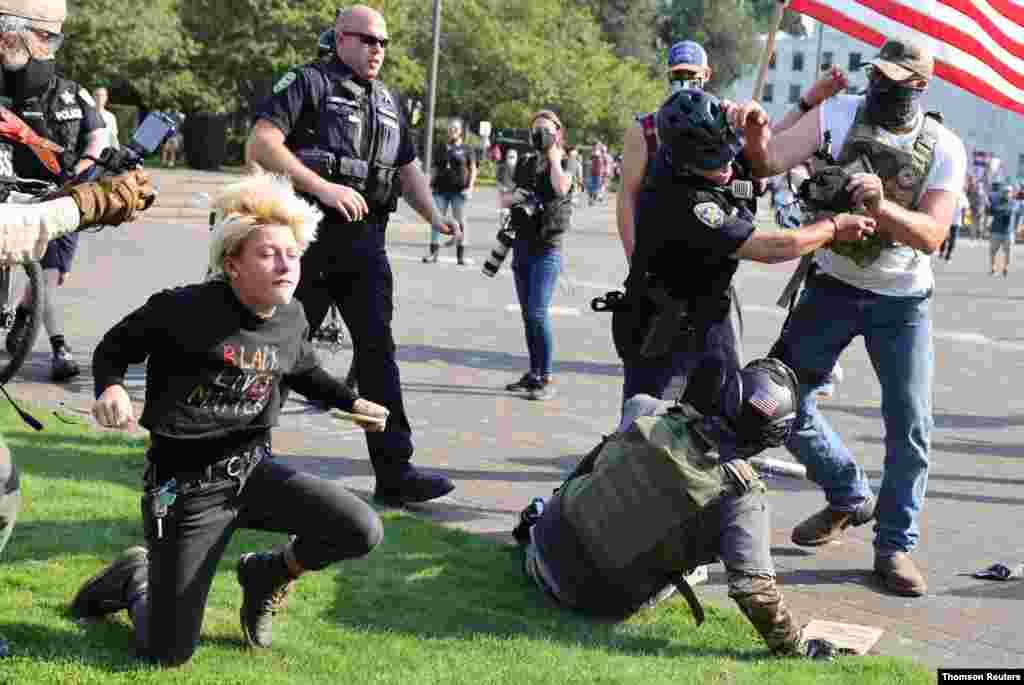 미국 오리건주 세일럼 의사당 앞에서 도널드 트럼프 미국 대통령 지지자들과 인종차별 항의 시위대가 몸싸움을 벌이며 충돌하자 경찰이 이를 제지하고 있다.