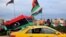 FILE - Libyans wave national flags from a cab in the capital, Tripoli, Feb. 25, 2021, during celebrations commemorating the 10th anniversary of the 2011 revolution that toppled longtime dictator Moammar Gadhafi.