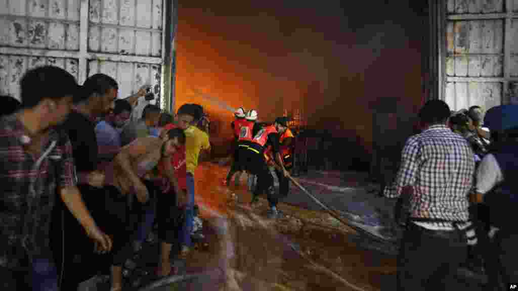 Firefighters try to extinguish fire after a cleaning materials factory was hit by an Israeli airstrike in Gaza City, Aug. 10, 2014. 