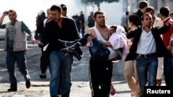 An injured Kurdish protester is carried by his friend as they clash with Turkish riot police in Diyarbakir, Oct. 8, 2014.