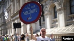 Seorang demonstran anti-lockdown dan anti-vaksin memegang plakat dalam aksi protes di Downing Street, di tengah pandemi COVID-19, London, Inggris, 14 Juni 2021. (REUTERS/Henry Nicholls)
