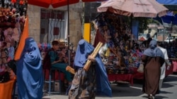 FILE - Burqa-clad women shop at a market in Kabul, Aghanistan, Aug. 23, 2021, following the Taliban's takeover of the country.