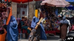 FILE - Burqa-clad women shop at a market in Kabul, Aghanistan, Aug. 23, 2021, following the Taliban's takeover of the country.
