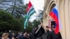 In this photo taken from video released by the AIASHARA Independent Agency, protesters gather around Abkhazian and Russian flags outside the parliament building of the Georgian separatist region of Abkhazia, Nov. 15, 2024.