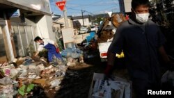 Locals clean a house, in the aftermath of Typhoon Hagibis, in Yanagawamachi district, Date City, Fukushima prefecture, Japan October 15, 2019.