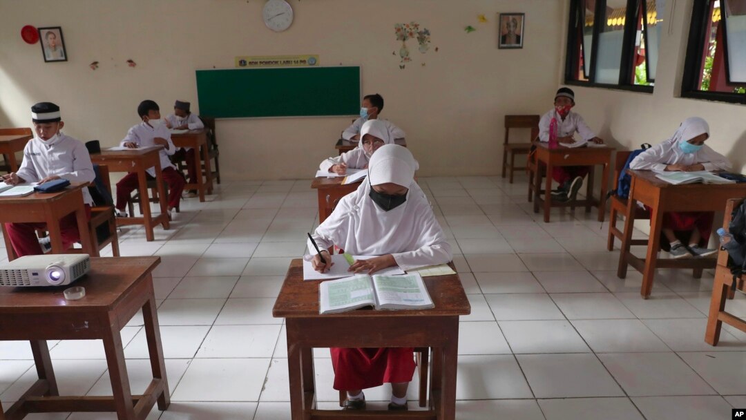 Siswa yang mengenakan masker duduk terpisah saat uji coba kelas dengan protokol COVID-19 di sebuah sekolah dasar di Jakarta, Jumat, 4 Juni 2021. (Foto: AP)
