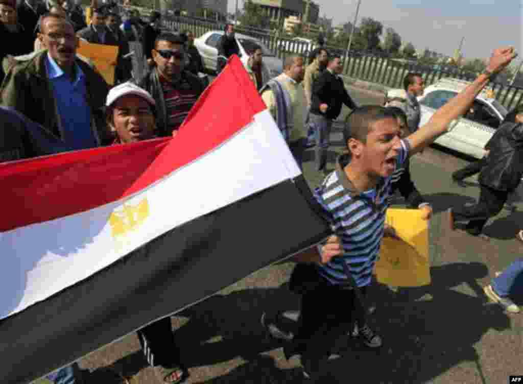 Anti-government protesters wave an Egyptian flag during a march in Cairo, Egypt, Friday, Feb. 11, 2011. Egypt's powerful military backed President Hosni Mubarak's plan to stay in office until September elections, but massive crowds outraged by his refusal