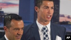 L'attaquant du Real Madrid, Cristiano Ronaldo, pose avec son agent Jorge Mendes après avoir reçu un trophée de bottine d'argent pour avoir marqué le plus de buts pour le club lors d'une cérémonie au stade Santiago Bernabeu à Madrid, en Espagne, 2 octobre 2015. 