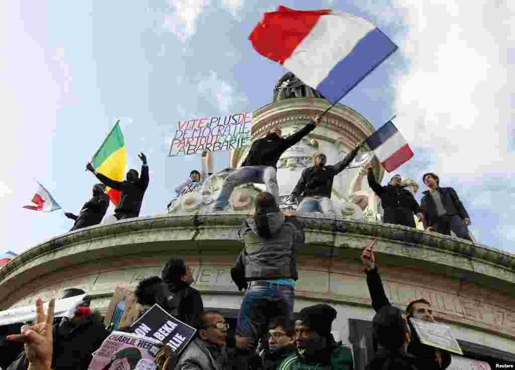 People holding a poster reading &quot;Quick more democracy everywhere against barbarism&quot; take part in a solidarity march in the streets of Paris, Jan. 11, 2015.