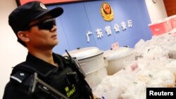 FILE L- A police officer stands guard next to seized drugs in Shenzhen, Guangdong province, China, April 24, 2018. A court in Guangdong province handed down sentences, April 30, 2019, to at least six foreigners involved in an international methamphetamine operation.